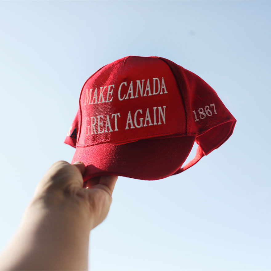 A guy holding up a red "Make Canada Great Again" hat.