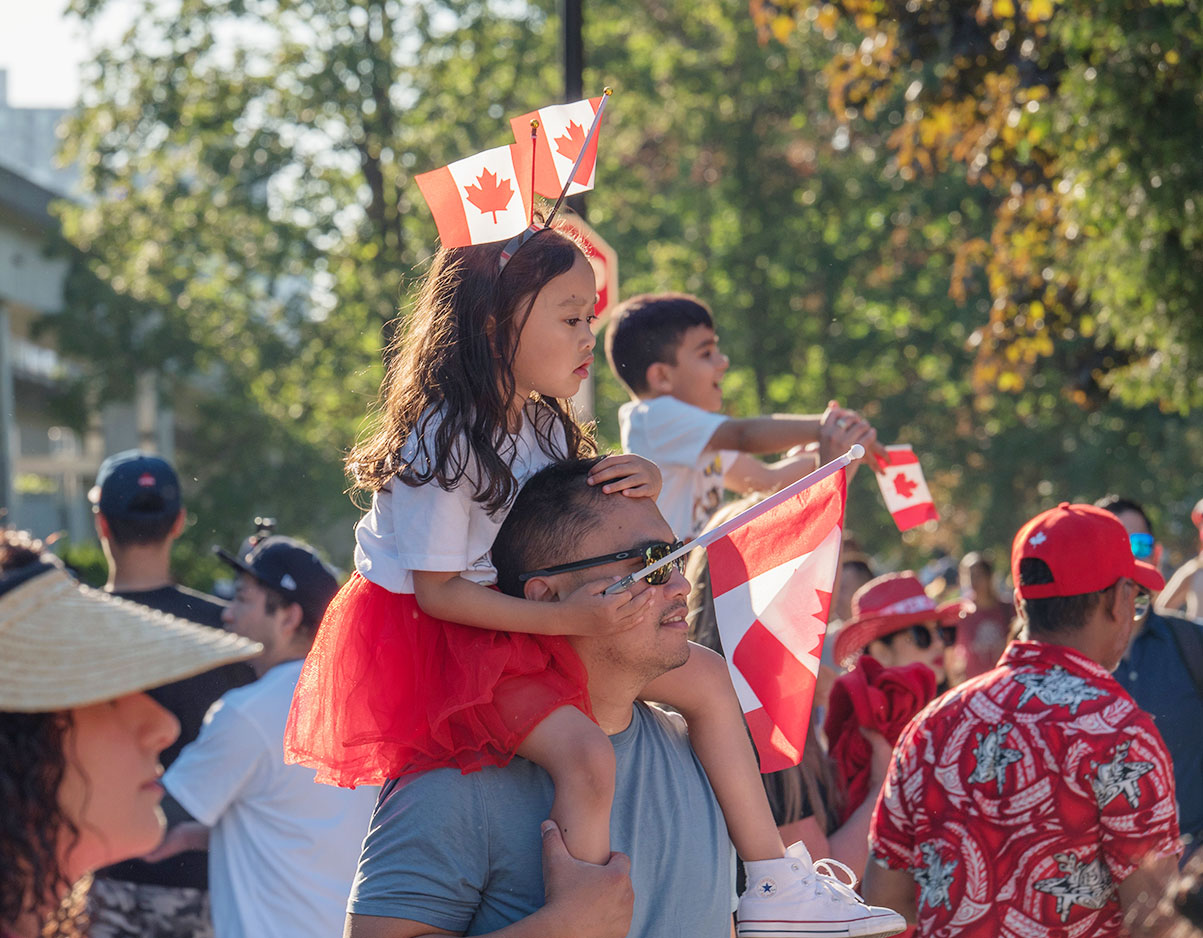 A girl on her dad's shoulders celebrating Canada Day.