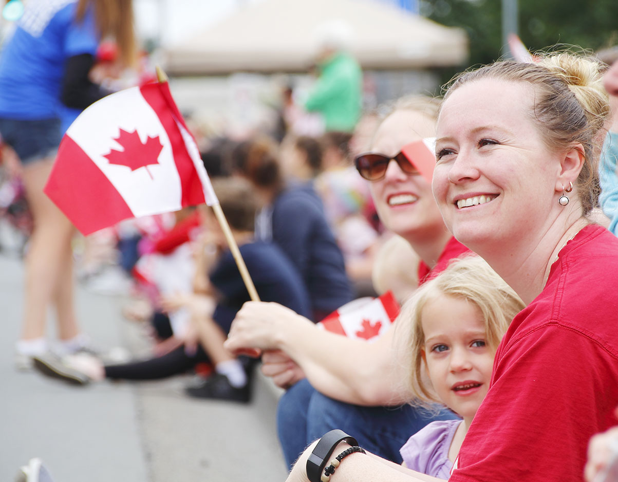 A bunch of people smiling and a Canada Day parade.