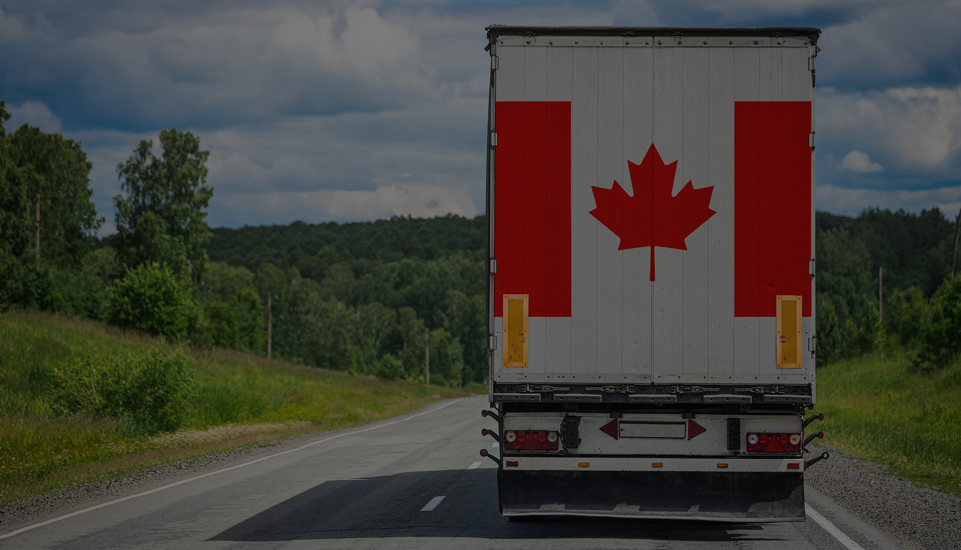 A truck with a Canada Flag on it driving on the highway